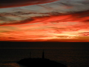 The sun is setting over the horizon with a pink and purple sky.